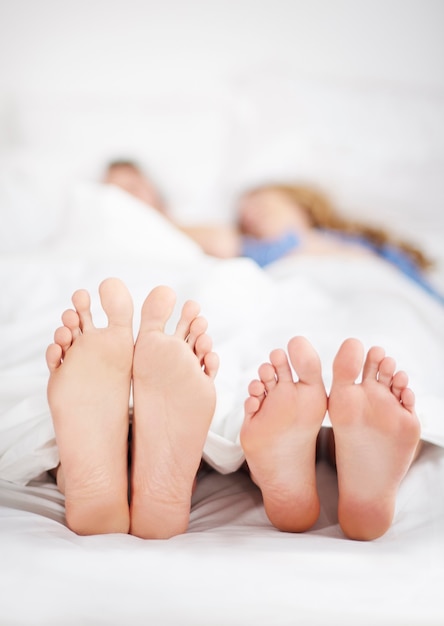 Couple feet sticking out of bed covers