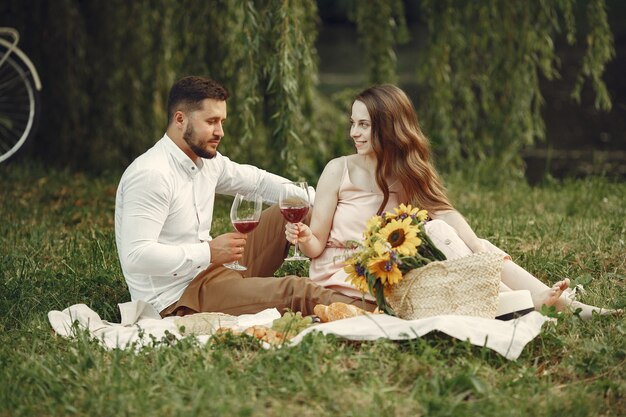 Couple in a field. Brunette in a white dress. Pair sitting on a grass.