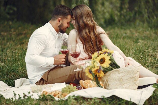 Couple in a field. Brunette in a white dress. Pair sitting on a grass.