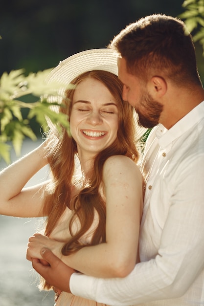 Couple in a field. Brunette in a white t-shirt. Pair sitting on a grass.