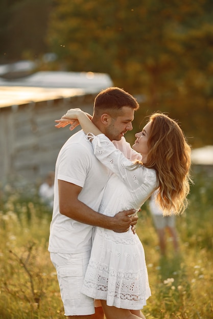 Couple in a field. Woman in a white dress. Sunset background.