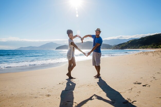 Couple forming heart at the shoreline