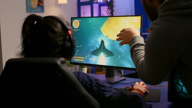 전문 헤드폰으로 집에서 강력한 컴퓨터에서 멀티 플레이어 게임을하는 게이머 커플