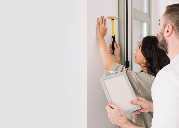 Free photo couple hammering nail for frame