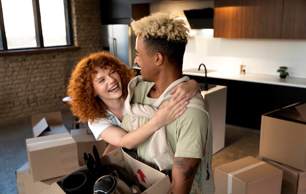 Couple handling cardboard boxes with belongings after moving together in new home