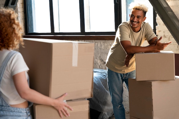 Foto gratuita coppia che maneggia scatole di cartone con effetti personali dopo essersi trasferiti insieme nella nuova casa