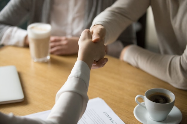 Couple handshaking businesswoman making deal in cafe, close up view