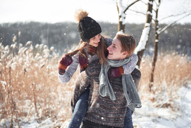Couple has fun and laughs. Young hipster couple hugging each other in winter park.
