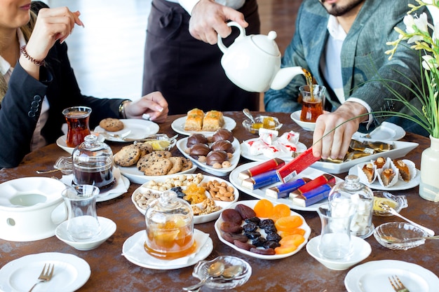 Couple have tea with cookies, sweets, dried fruits and nuts and baklava