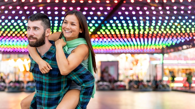 Free photo couple having fun next to bumper cars ring