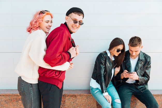 Couple having fun while other pair looking in smartphone