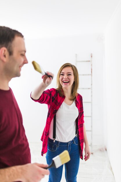 Couple having fun while painting walls