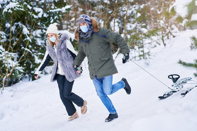 雪​を​かぶった​マスク​で​そり​を​楽しんでいる​カップル​。​高​品質​の​写真