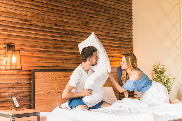 Free photo couple having pillow fight on bed