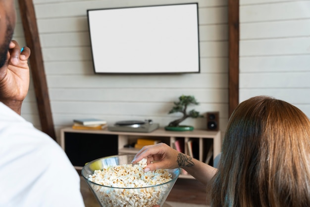 Free photo couple having some popcorn while watching a movie