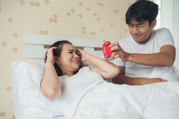 Couple having trouble with getting up early in the morning on the bed