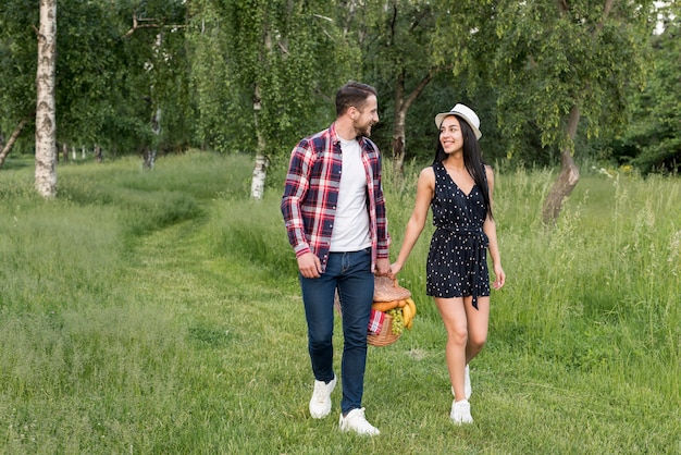 Foto gratuita coppia con una passeggiata in possesso di un cestino da picnic