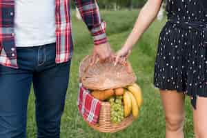 Free photo couple having a walk holding a picnic basket