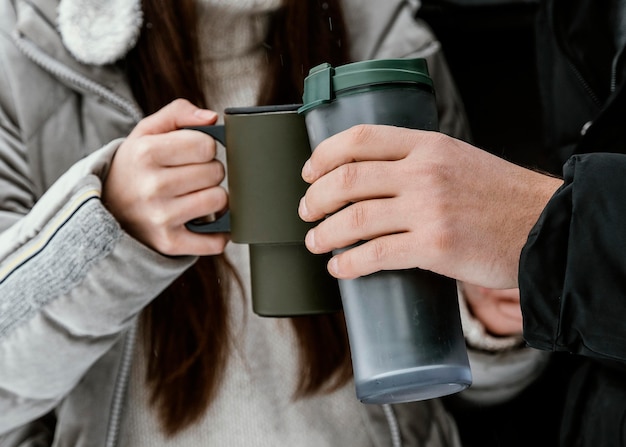 Couple having a warm drink in the car's trunk while on a road trip