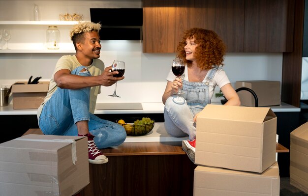 彼らの新しい家の台所で一緒にワインを持っているカップル