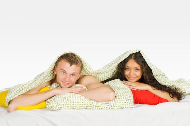 Free photo couple hiding under covers in bed