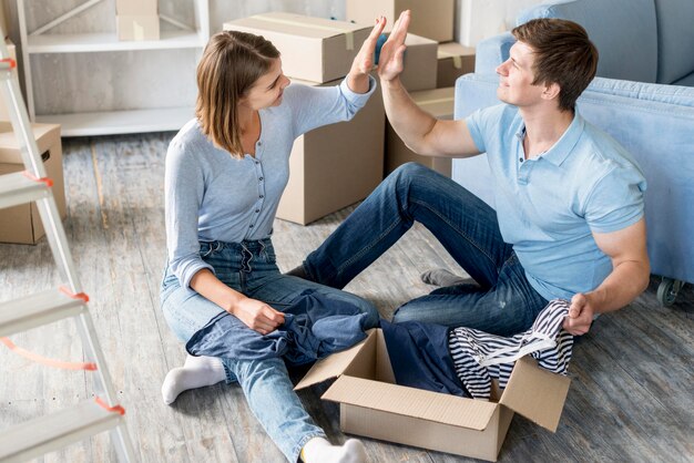 Couple high-fiving each other while packing to move
