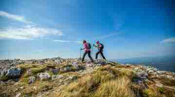 Free photo couple hiking on nanos plateau in slovenia against a blue sky