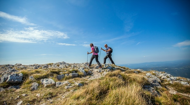 Couple hiking on Nanos Plateau in Slovenia against a blue sky