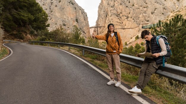 Couple hitch-hiking for a car