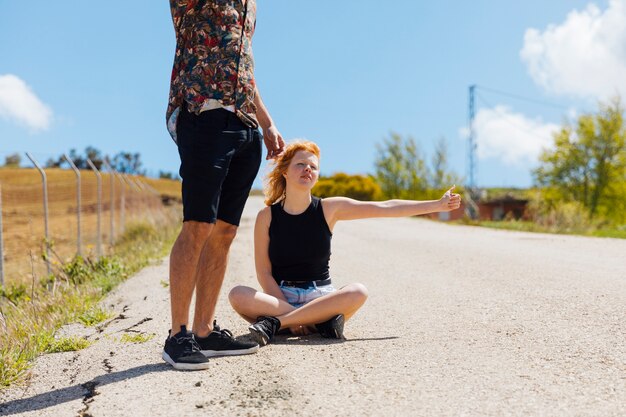 Couple hitchhiking on deserted road
