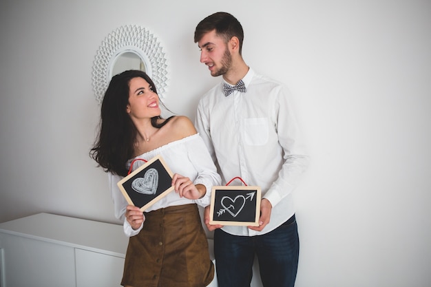 Free photo couple holding black slates with drawn hearts