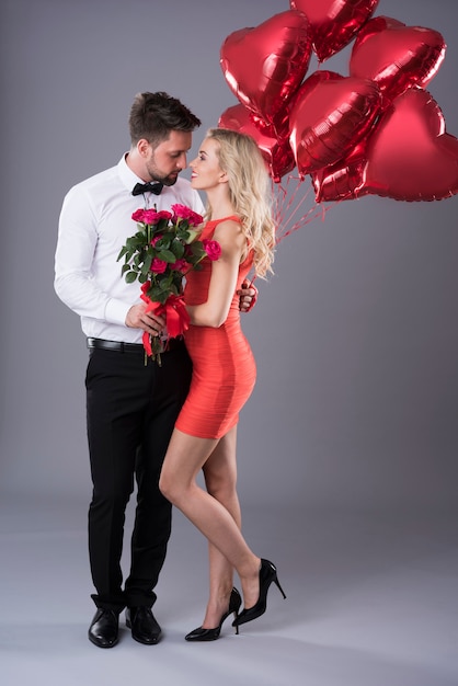 Couple holding a bunch of flowers and balloons