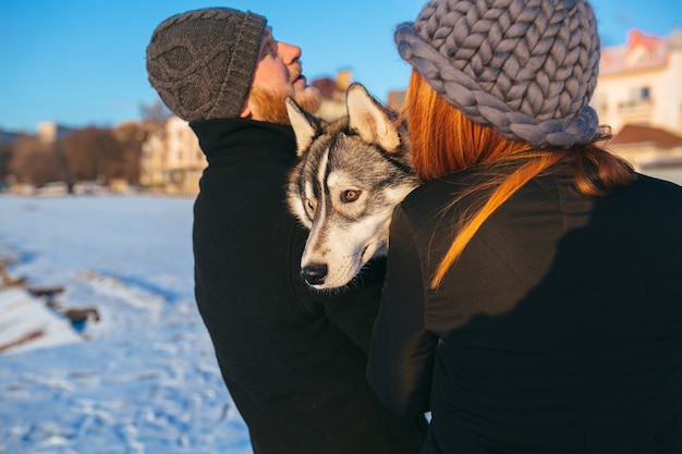 Free photo couple holding dog on hands while walking