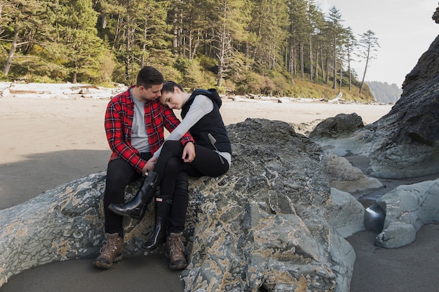 Couple holding each other at the beach on rock