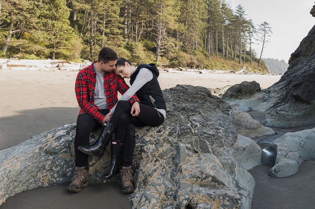 岩のビーチでお互いを保持しているカップル