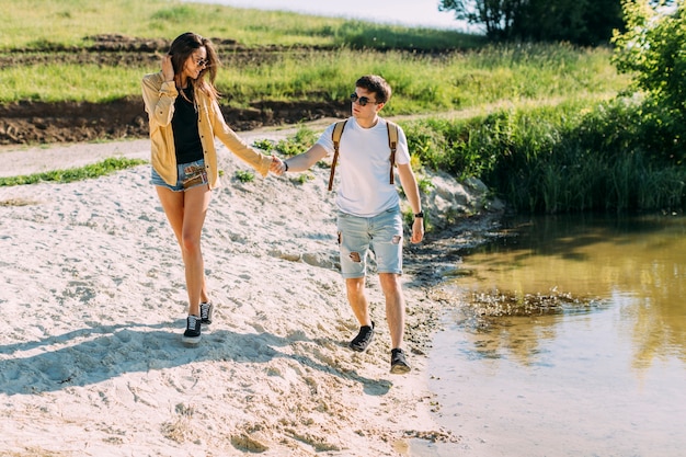 Free photo couple holding each other's hand hiking near the coast