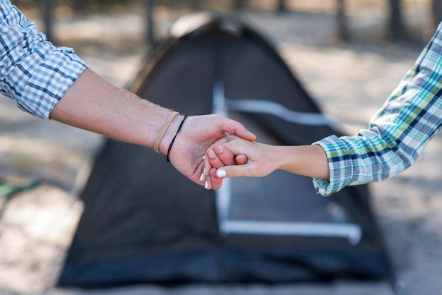 Free photo couple holding hands blurred tent