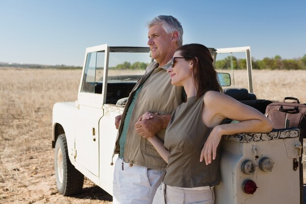 Couple holding hands by vehicle on field