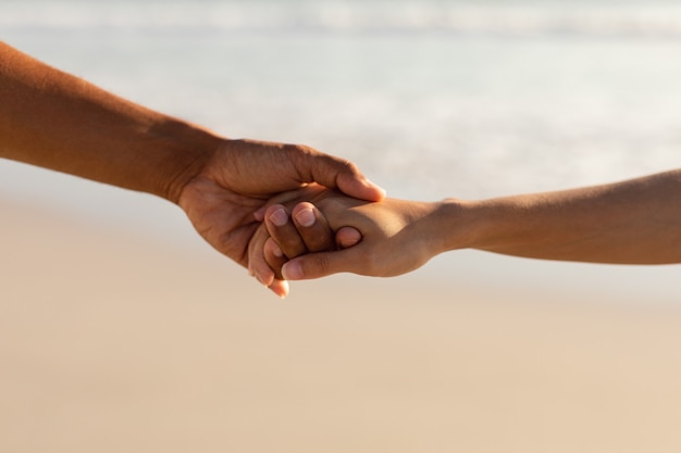 Couple holding hands of each other on the beach