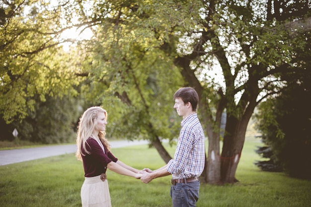 Couple holding hands in a garden surrounded by greenery under sunlight