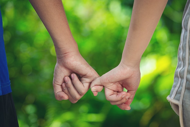 Free photo couple holding hands in green meadow.