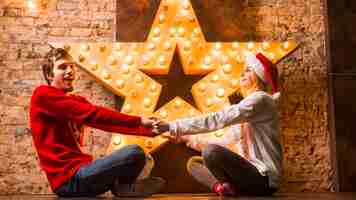 Бесплатное фото Пара, держась за руки перед рождественские украшения звезды