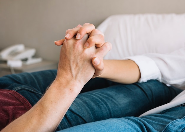 Free photo couple holding hands lying on bed at home