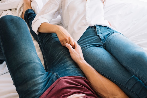 Free photo couple holding hands lying on bed