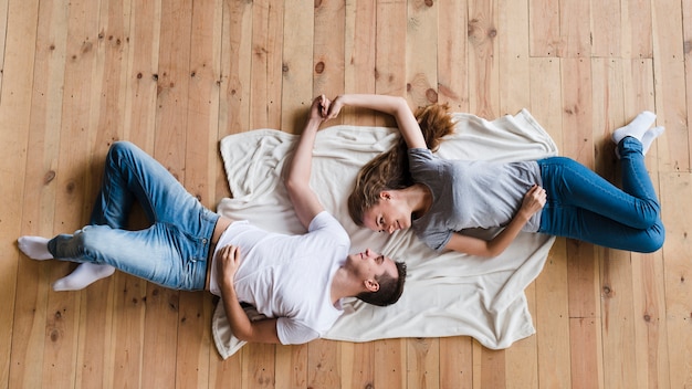 Free photo couple holding hands on sheet on floor