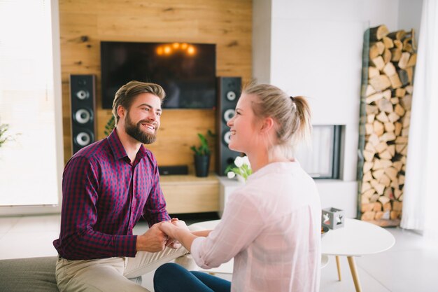 Couple holding hands on sofa at home