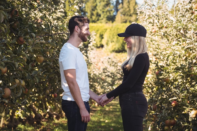 手を繋いでいるとリンゴ園に立っているカップル