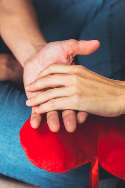 Couple holding hands on toy heart 