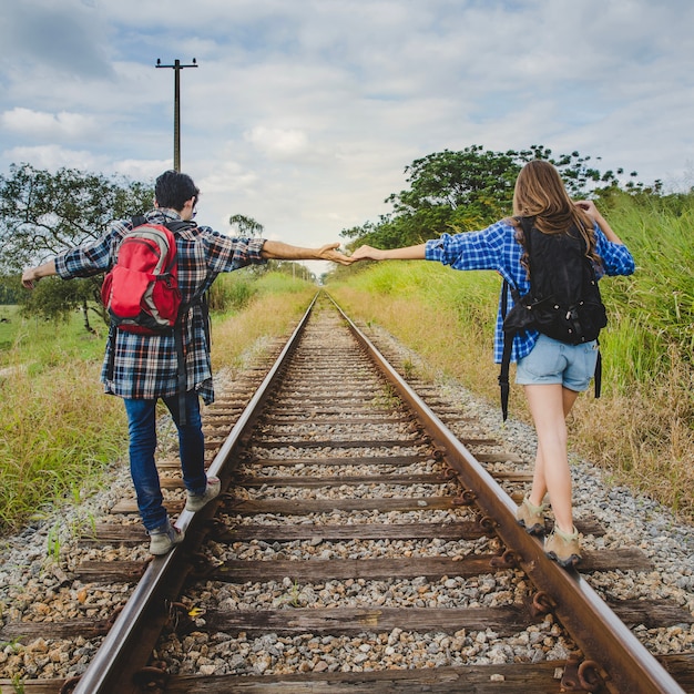 Couple holding hands on train tracks