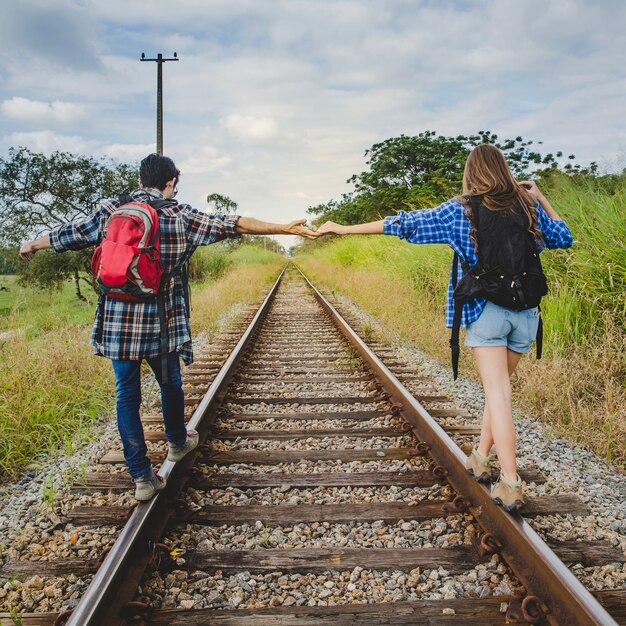 Couple holding hands on train tracks